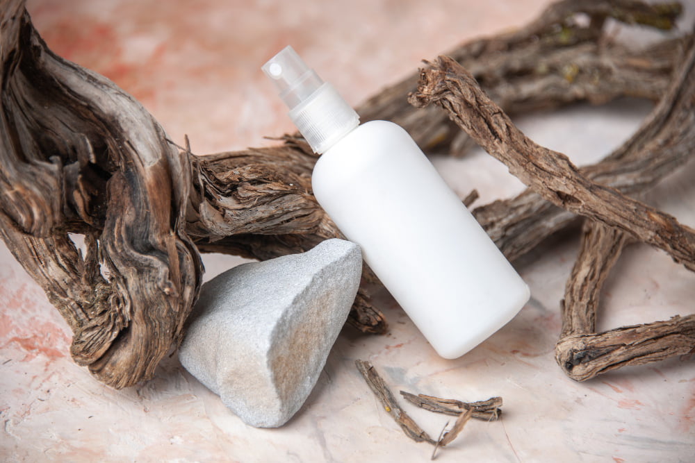 A bottle of the best thin hair shampoo placed on stones with herbs surrounding it