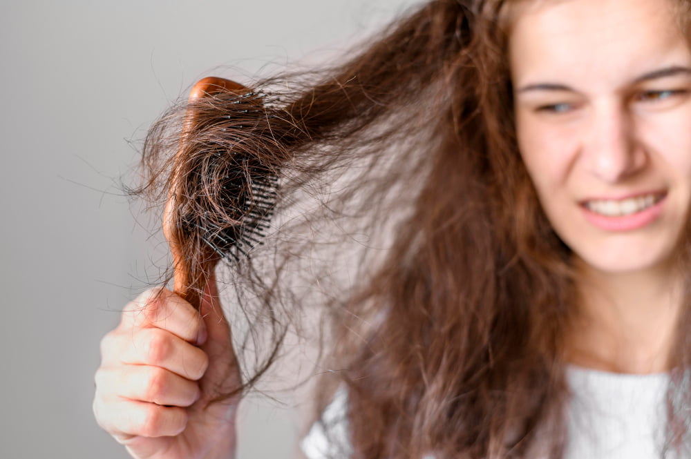 Girl combing very dry hair with many tangles, highlighting the need for hair masks for dry hair.